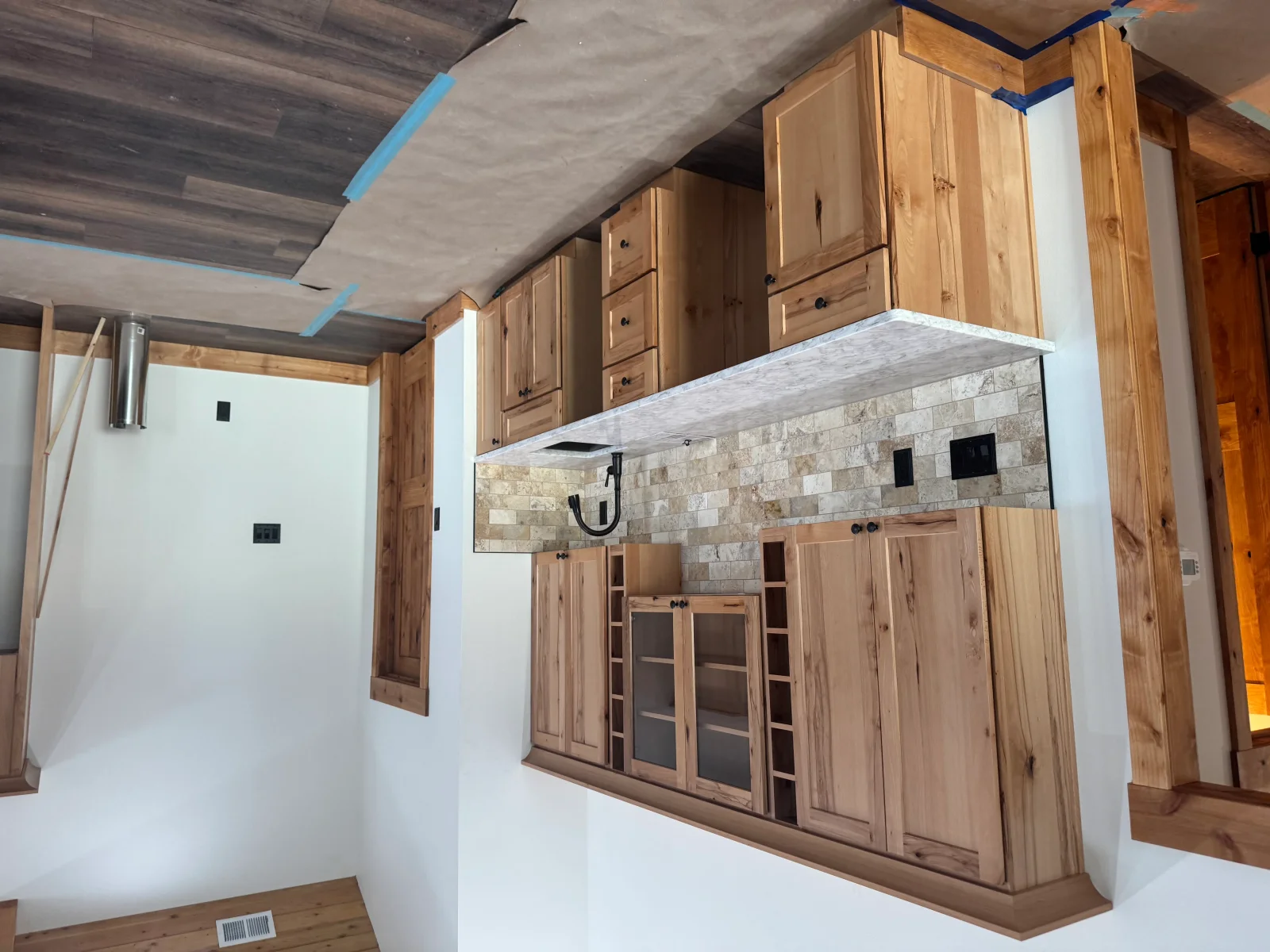 Kitchen with wood cabinetry, stone tile backsplash, concrete countertop, and recessed lighting