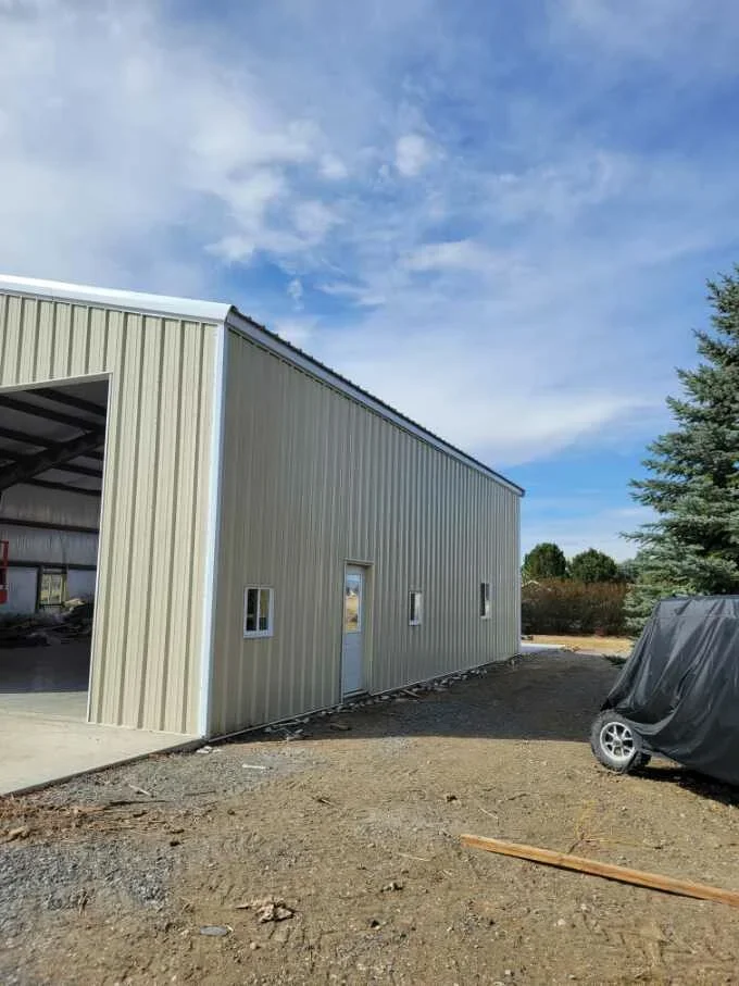 Metal building addition with corrugated steel siding, concrete foundation, and gravel site preparation