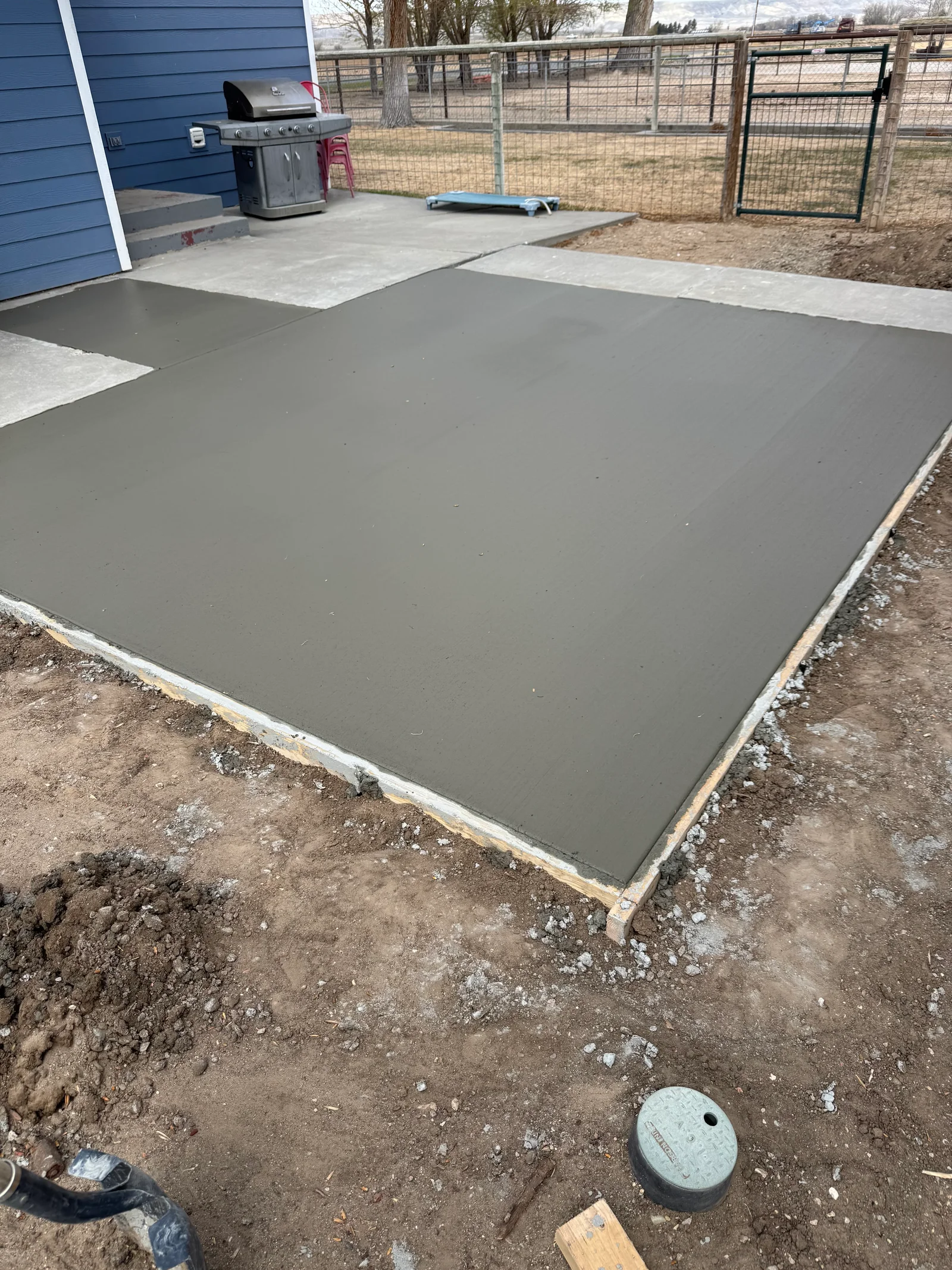 Freshly poured gray concrete patio with white edge forms and finished surface