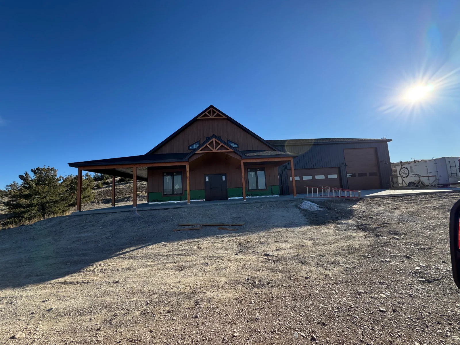 Brick and metal commercial building with gabled metal roof, timber truss details, and covered entry portico