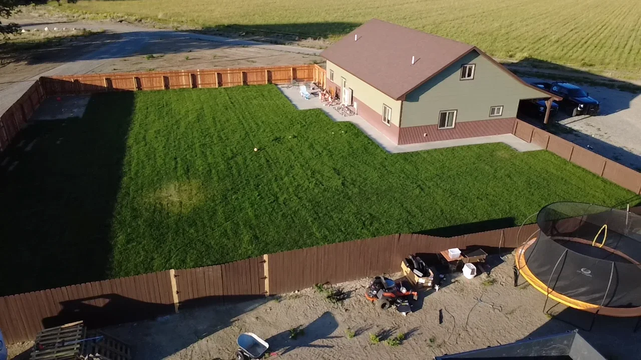 Corrugated metal fencing and sod installation around residential property with established lawn