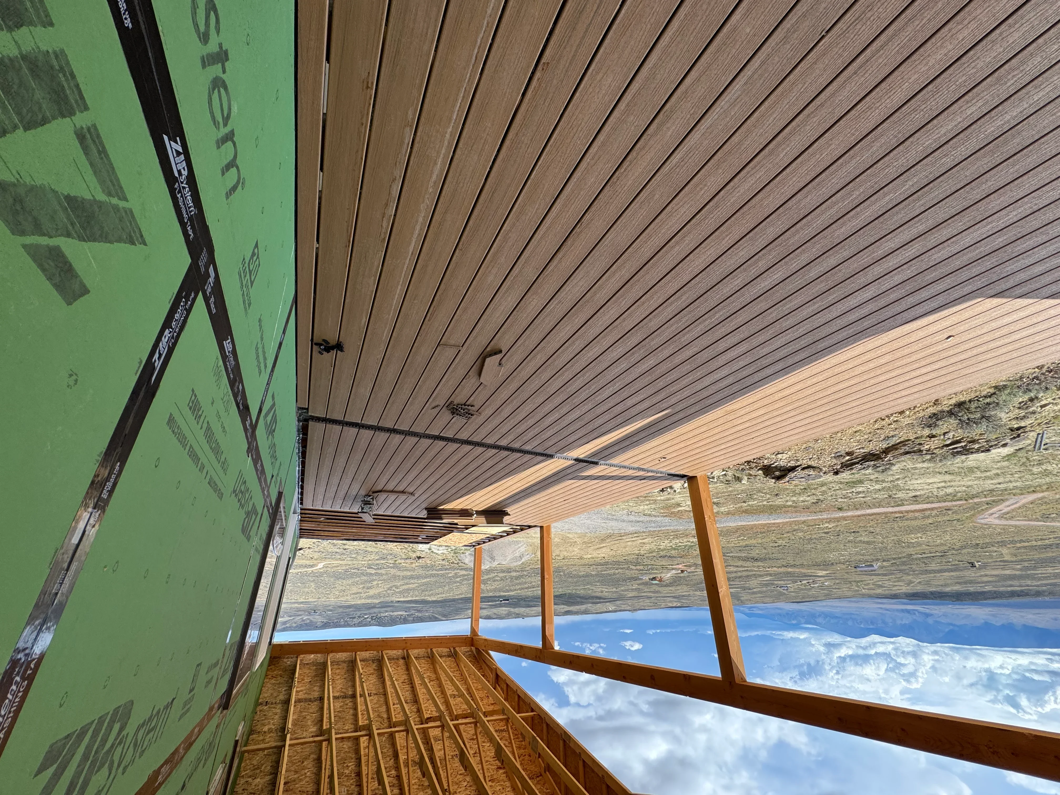 Composite deck with pressure-treated framing, wooden posts, and metal roof overhang structure