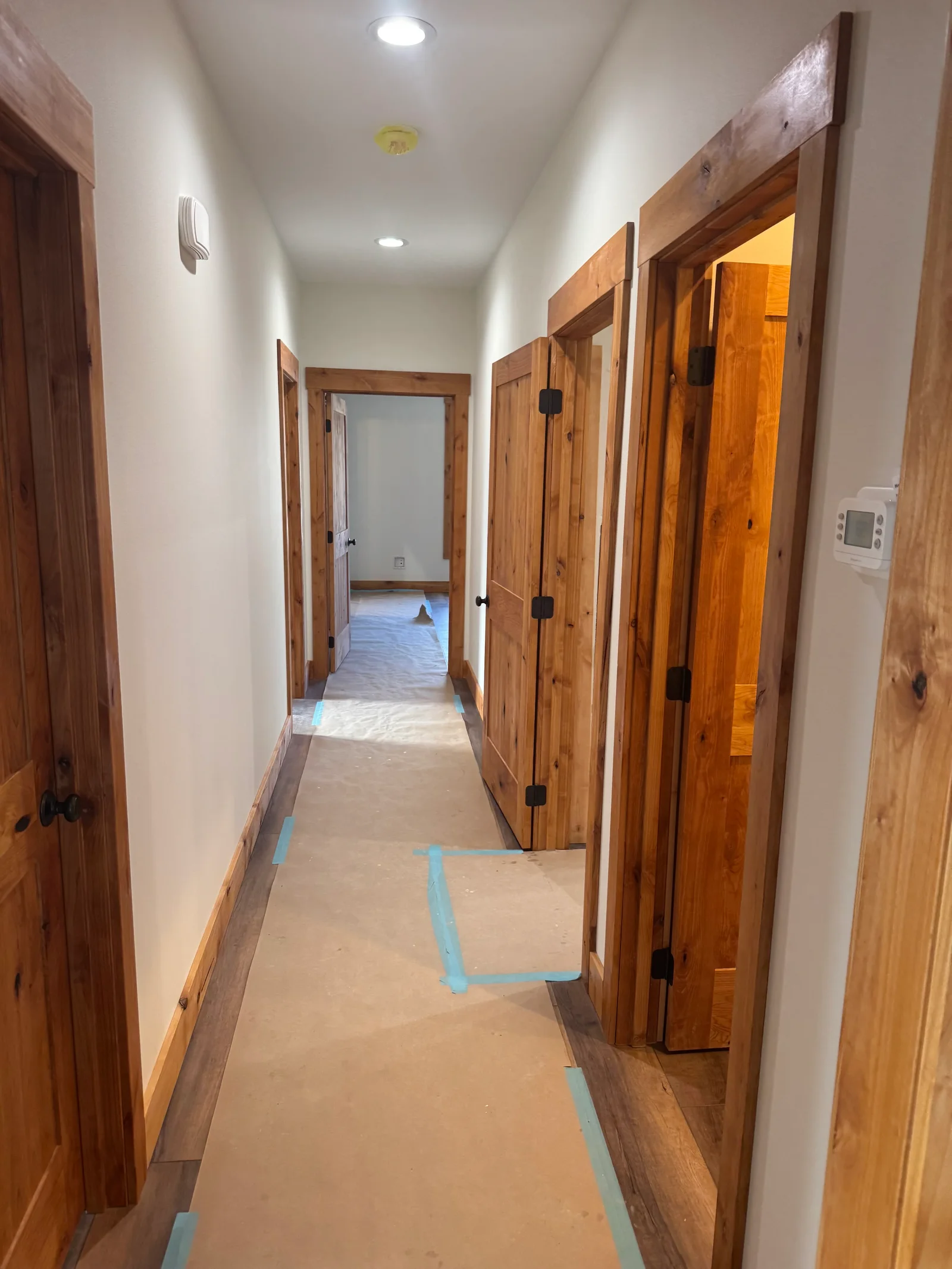 Hallway with white walls, recessed lighting, and multiple custom wood doors with black hinges