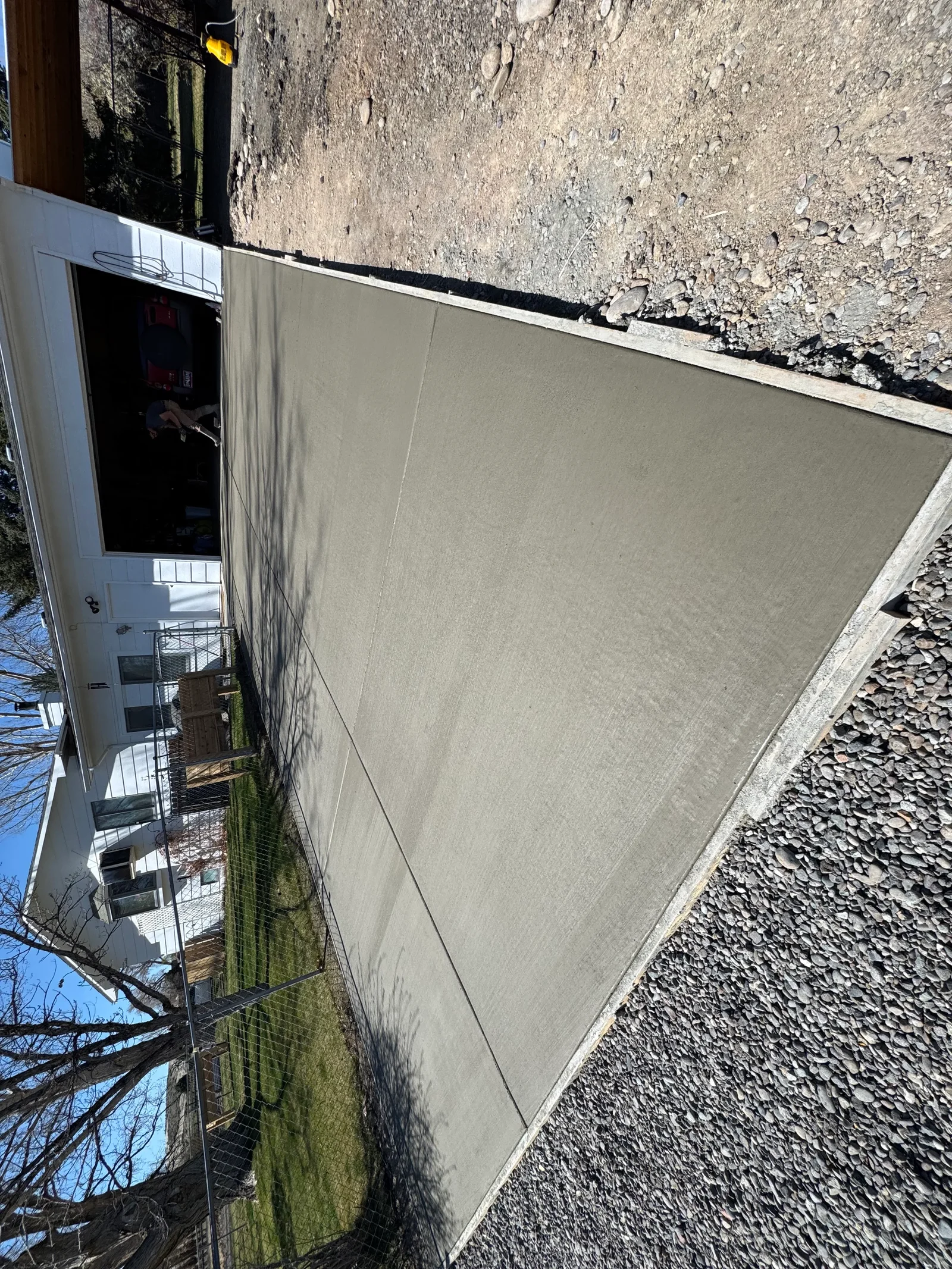 Concrete retaining wall with smooth finish, gravel base, and stone aggregate backfill