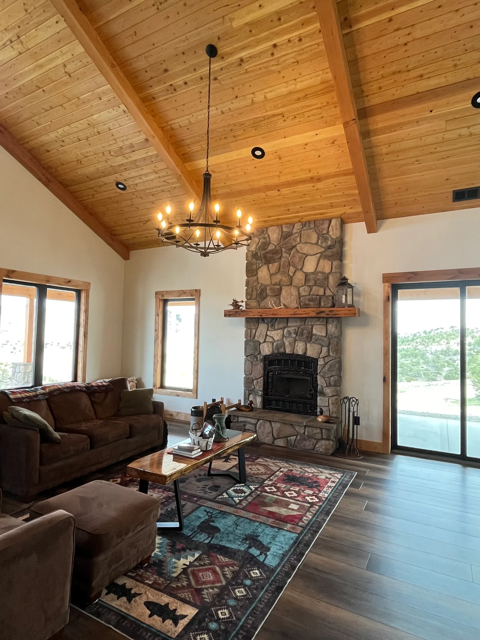Living room with exposed wood beam ceiling, stone fireplace, and glass doors
