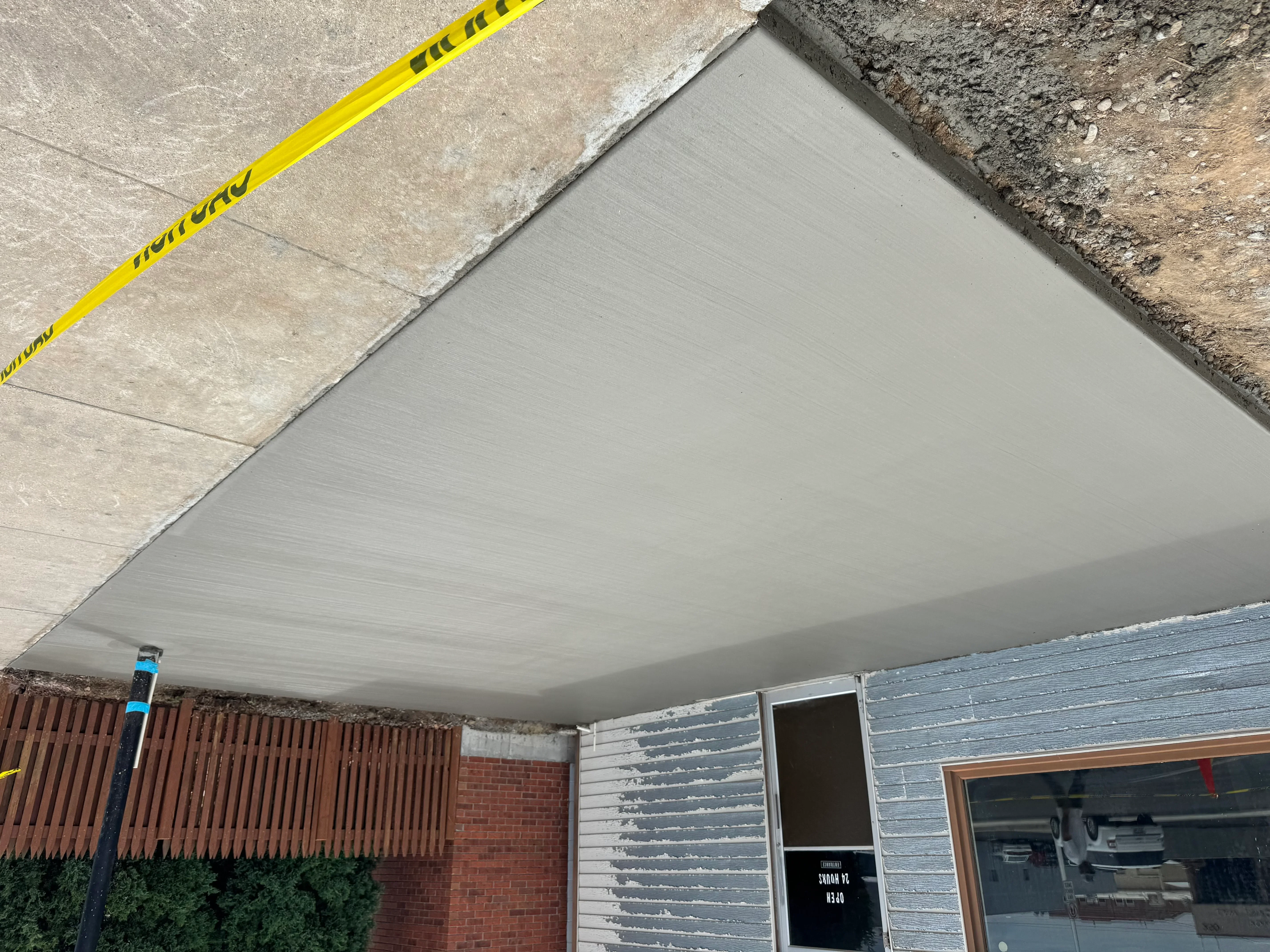 Gray soffit panel installation under concrete overhang with brick and siding integration