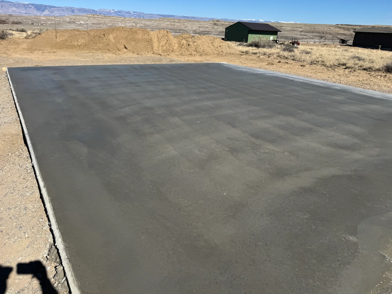 Finished concrete pad with steel edge forms on prepared ground