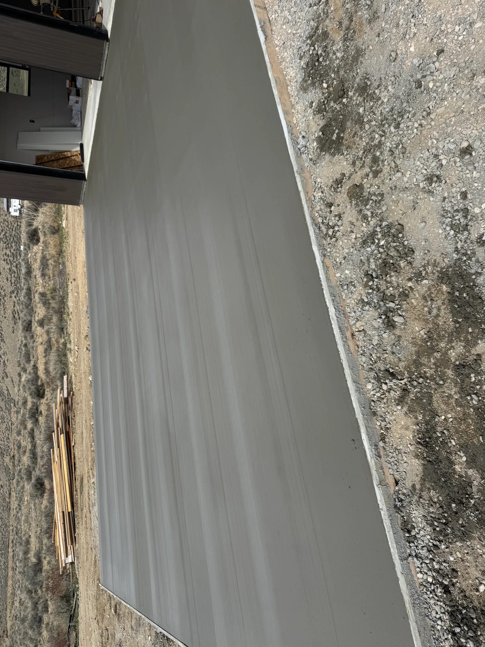 Newly poured concrete driveway with smooth gray finish and white edge trim